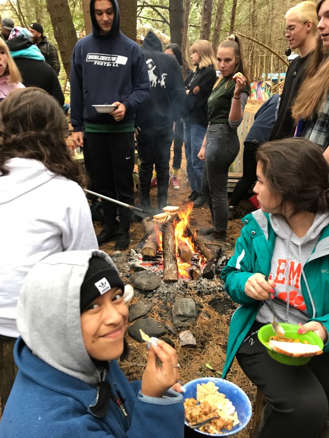 Students cooking and eating around the campfire