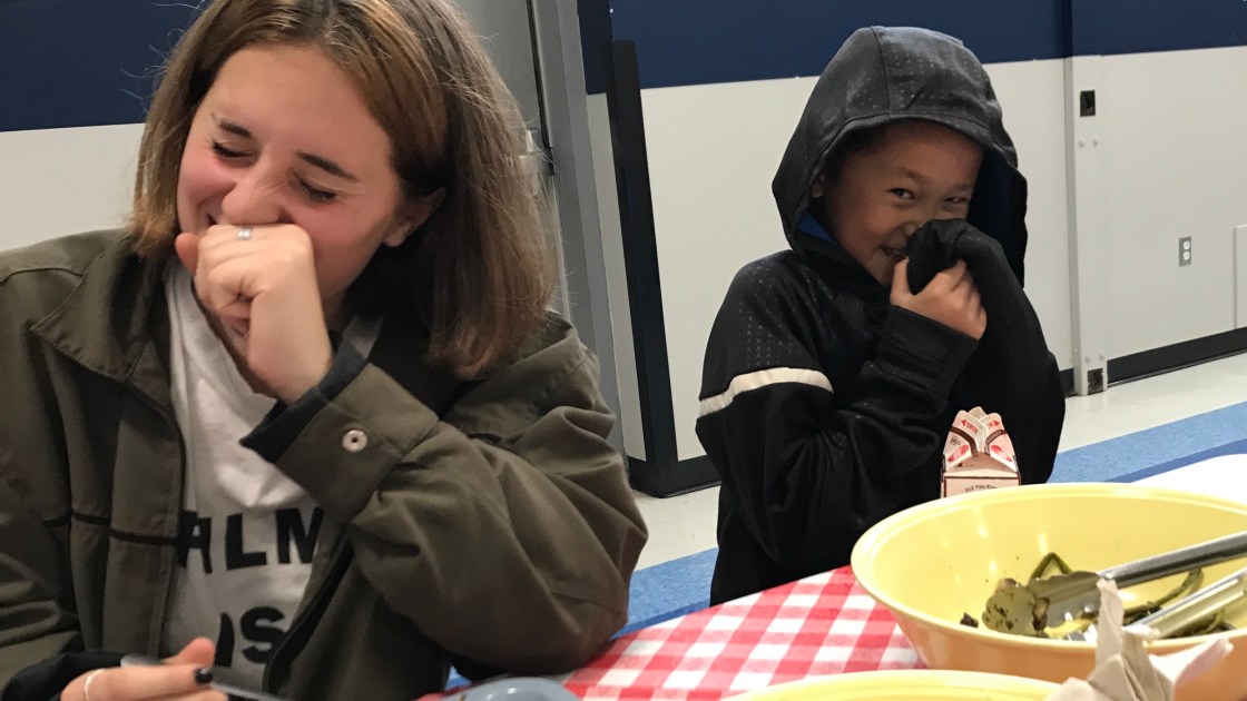 High school student and kindergartner laughing over lunch
