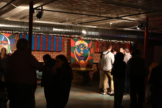 Students and others mingle in event space in front of painting