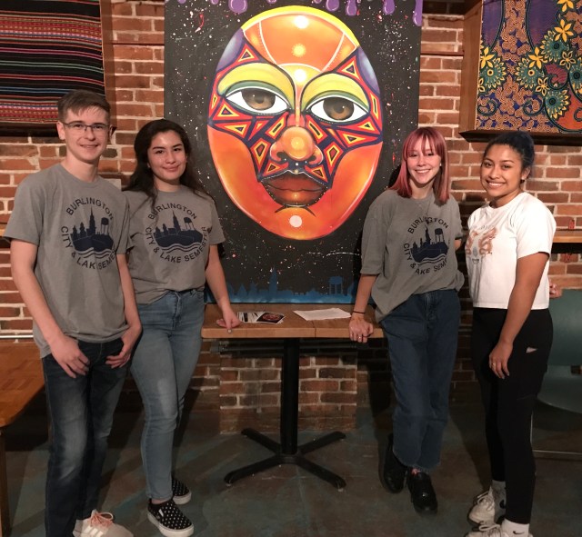 Four students in front of painting