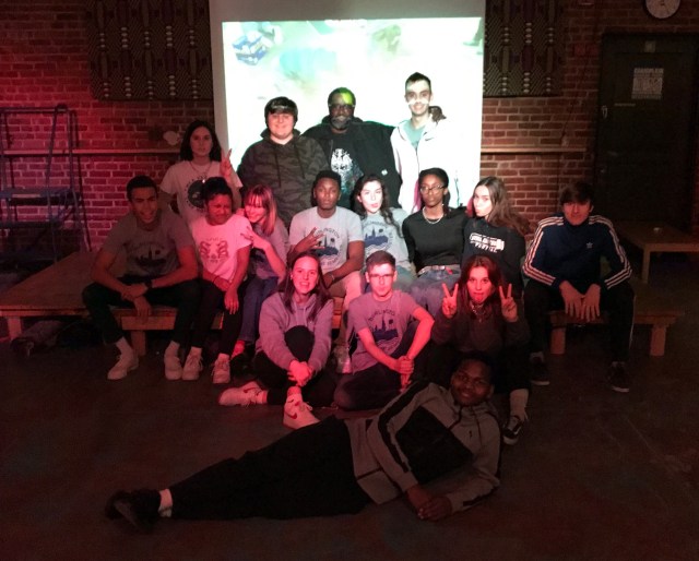 Group shot of students with artist in front of projection