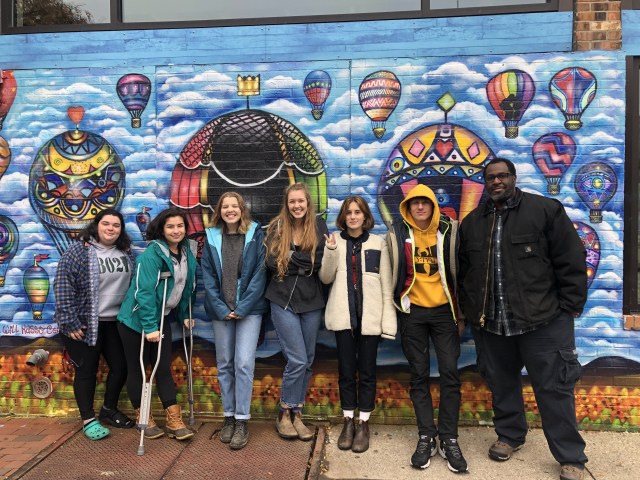 Artist and students in front of colorful hot air balloon mural